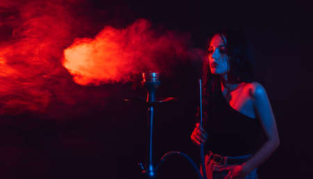 A young girl enjoys smoking a hookah, sheesha. Photo with space for textの写真素材
