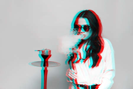 An attractive woman in a hipster image smokes a hookah, sheesha and enjoys smoking. Black and white...