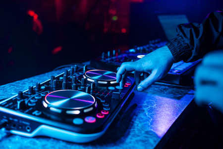 DJ console for mixing music with hands and with blurred people dancing at a night club partyの写真素材