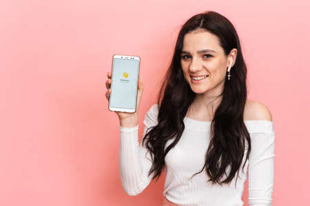 VICHUGA, RUSSIA - February 18, 2021. A girl with headphones is holding a smartphone with the Club house app on the screen. Clubhouse Drop-in audio is a voice-activated social media app.のeditorial素材