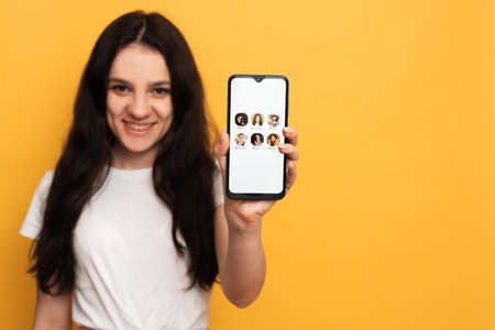 The girl is holding a smartphone with the Club house app interface on the screen. Clubhouse Drop-in...
