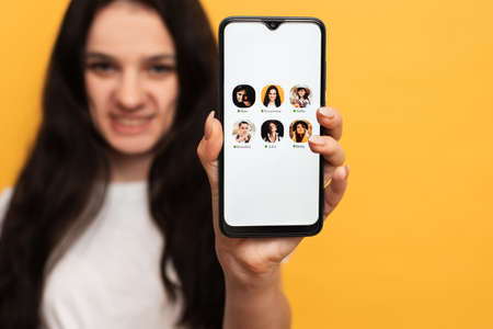 The girl is holding a smartphone with the Club house app interface on the screen. Clubhouse Drop-in audio is a voice-activated social media app.の写真素材