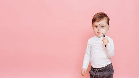funny boy looking through magnifying glass with surpriseの写真素材