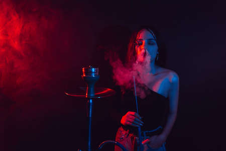 Model girl smokes hookah. The girl exhales with pleasure. Color lightの写真素材