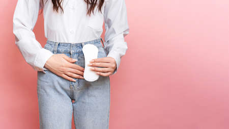 Studio shot of a young girl feeling the pain of menstruation with a Pantyliner in her hands. Space for the text.の写真素材