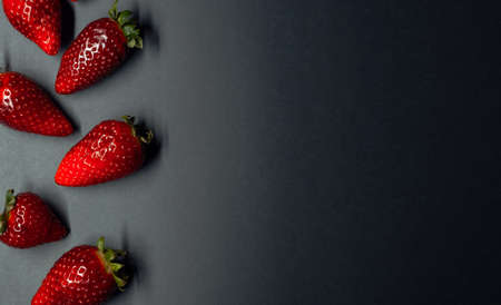 berries of ripe and juicy strawberries on a dark background. space for your text