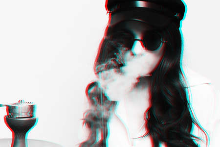An attractive woman in a hipster image smokes a hookah, sheesha and enjoys smoking. Black and white...