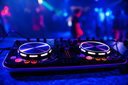 DJ console for mixing music with blurry people dancing at a nightclub party