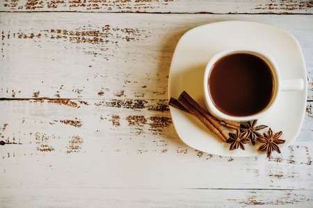 a Cup of coffee with cinnamon sticks on a light wooden background. space for textの写真素材