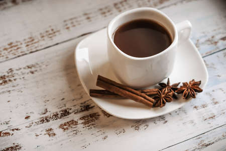 a Cup of coffee with cinnamon sticks on a light wooden background.の写真素材