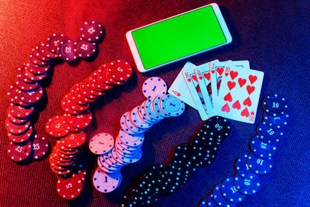 The concept of an online casino: playing cards, betting chips and a smartphone with a copy space and...