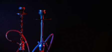 Modern hookah, shisha on a black background with colored lighting and smoke. Place for your text
