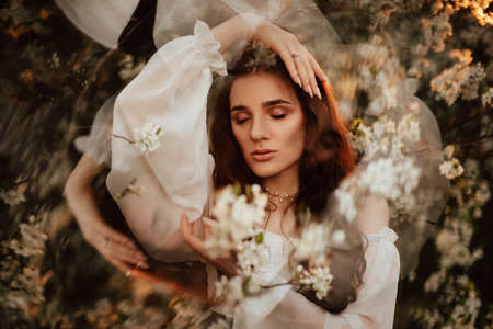 Portrait of a romantic girl, like a forest fairy, in a blooming garden with elements of phantasmagoria. The concept of fantasy, fairy tales.の写真素材