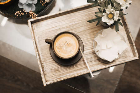 A cup of cappuccino sits on a wooden tray on the table. Waiting for a cosmetic procedure.の写真素材