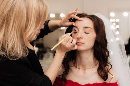Girl makeup artist brush to apply eye shadow on the eyelid of the model.の写真素材