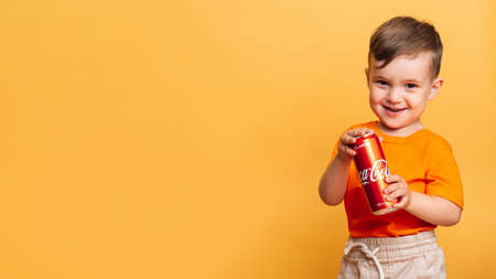 Vichuga. Russia. February 27, 2020: happy boy stands with a can of Coca-Cola and smiles. The products contain a lot of sugar and are harmful to children. Place for your textのeditorial素材