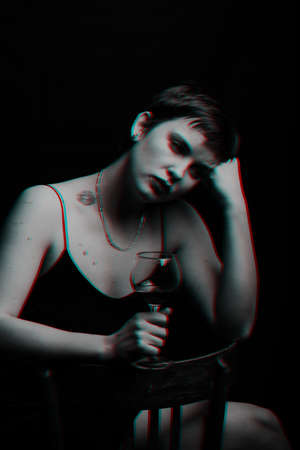beautiful young girl drinks red wine and is sad. Black and white with glitch effectの写真素材