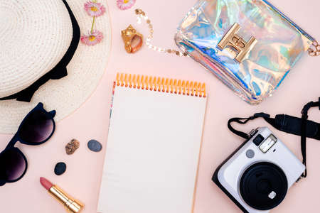 summer travel accessories. camera, hat, glasses and a flat Notepad top view lay flat on a light backgroundの写真素材
