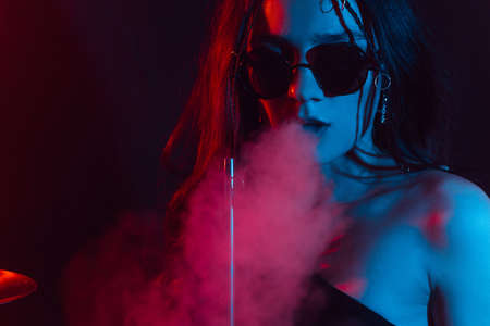 Hookah atmosphere. Large portrait of a girl who enjoys smoking a hookah, sheesha.の写真素材