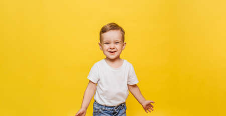 Portrait of a cute laughing little boy on a yellow background. Copy space.の写真素材