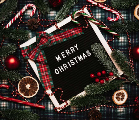 Merry Christmas lettering in plastic letters on an letter board.There are caramel canes, balls, cones and fir branches and dried orange all around.Top view.Flatley.Christmas card.の写真素材