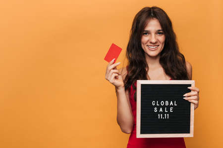 A smiling Caucasian woman holding a credit card and a message board with the inscription on it...