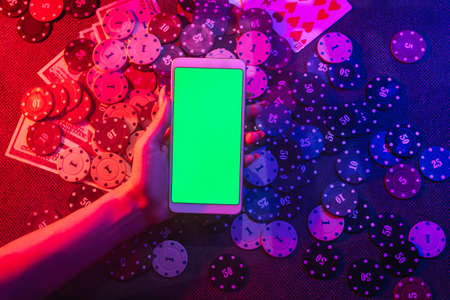 The concept of an online casino: playing cards, betting chips and a smartphone with a copy space in...