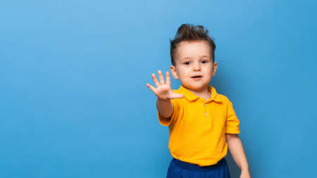 Cute little grimaces stands on a blue background. Funny kidの写真素材