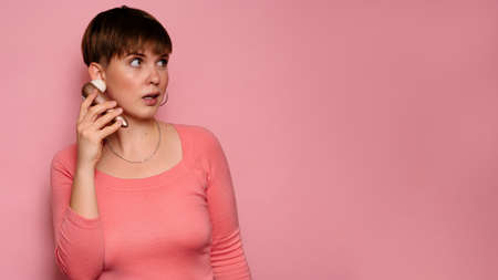 A studio shot of a young woman holding a vacuum vibrator in her hands. Bright pink background. The concept of female orgasm. A place for your text or advertisement.の写真素材