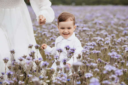 happy smiling boy runs through a blooming fieldの写真素材
