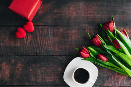 Bouquet of red tulips on a wooden background with a Cup of coffee. Spring flowers. Mothers day...
