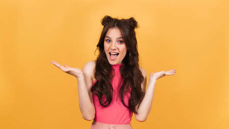 Studio portrait of a cheerful emotional girl on a bright yellow background.の写真素材