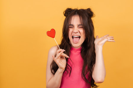 A surprised young funny girl is holding a lollipop in her hands and fooling around.の写真素材