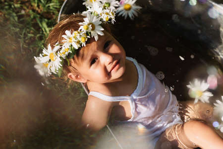 A baby smiling girl is bathing in a bathtub standing in the garden, on a hot sunny summer dayの写真素材