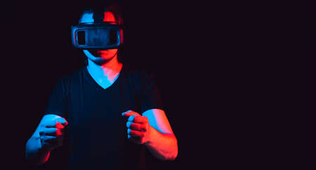 A young man in virtual reality glasses is playing video games. with space for textの写真素材