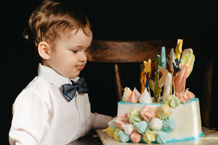 a little boy next to a cake for his birthdayの写真素材