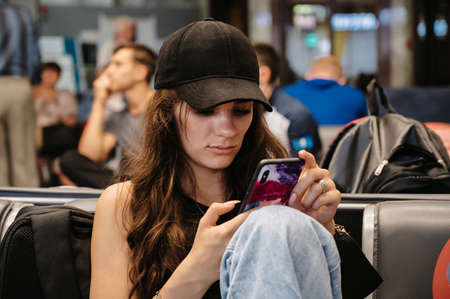 RUSSIA, MOSCOW: August 19, 2021 - A young girl is a tourist, sitting on the phone while waiting for departure. Station waiting roomのeditorial素材