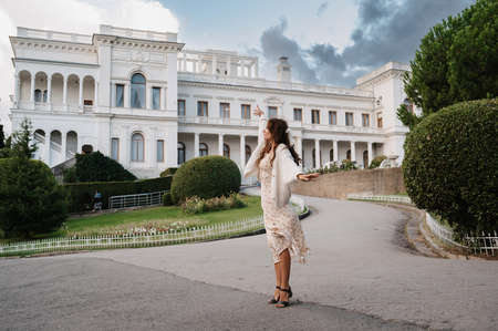 CRIMEA, LIVADIA - SEPTEMBER 02.2021: Photo of a young tourist girl in a vintage white dress against the background of the Livadia Palace.のeditorial素材