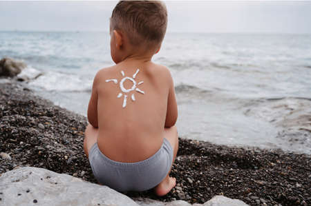 Close-up of a boys shoulder with a sunscreen pattern made with sunscreen. Protection about the babys skin.の写真素材