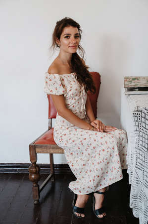 Portrait of a young woman in a vintage womens dress, sitting on vintage furniture.の写真素材