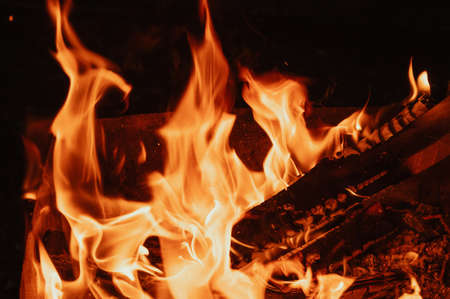 A bonfire in close-up, flames, charred pieces of logs and ashes in the open air. Camping.