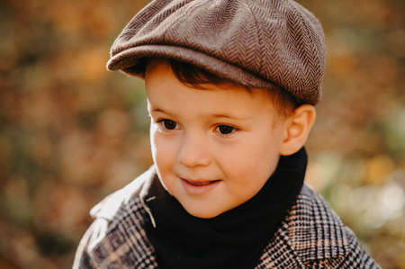 Portrait of a happy child boy walking among golden trees in the autumn in the park.
