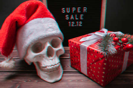 Glitch effect. The text of the sale 12.12 on the letter board with a gift box and a skull in a Santa Claus hat. Design to promote the winter sale at the end of the year.の写真素材