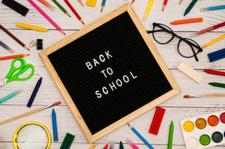 Text: Back to school soon on a wooden letter board. buying stationery, flat, white wooden background. Autumn school fees.の写真素材