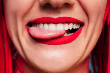 Sexy female lips. Funny open mouth with tongue sticking out. A smiling young girl. Beautiful face close-up.の写真素材