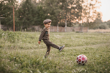 A boy is playing football in the countryside. The joyful childhood of the baby. Active sports.の写真素材