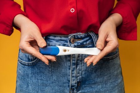 Close-up of female hands holding a positive pregnancy test. The concept of pregnancy, motherhood.の写真素材