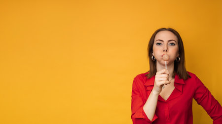 A surprised young funny girl is holding a lollipop in her hands and fooling around. A place for your text.の写真素材