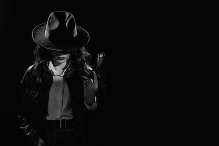 Silhouette: a female detective in a coat and hat with a gun in her hands. Dramatic noir portrait in the style of books and detective films of the 1950s. black and white snapshotの写真素材
