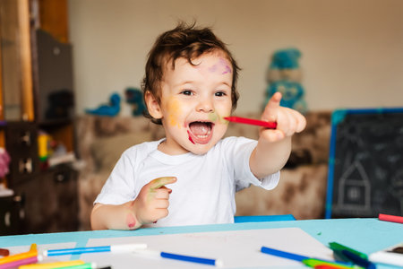 Happy little boy draws with colorful markers in an albumの写真素材